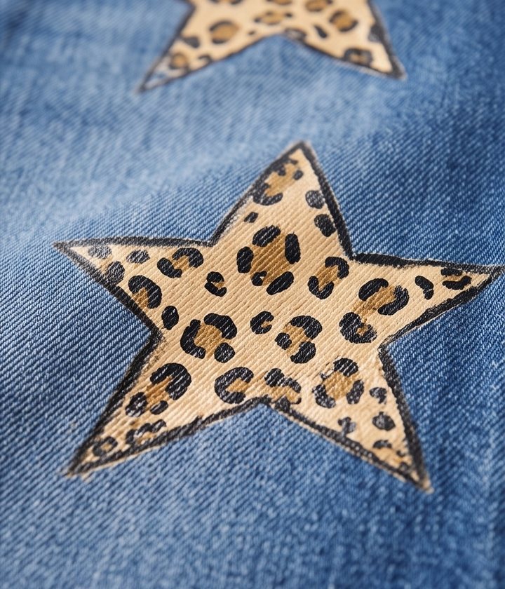 Dettaglio di stelle leopardate dipinte a mano su denim