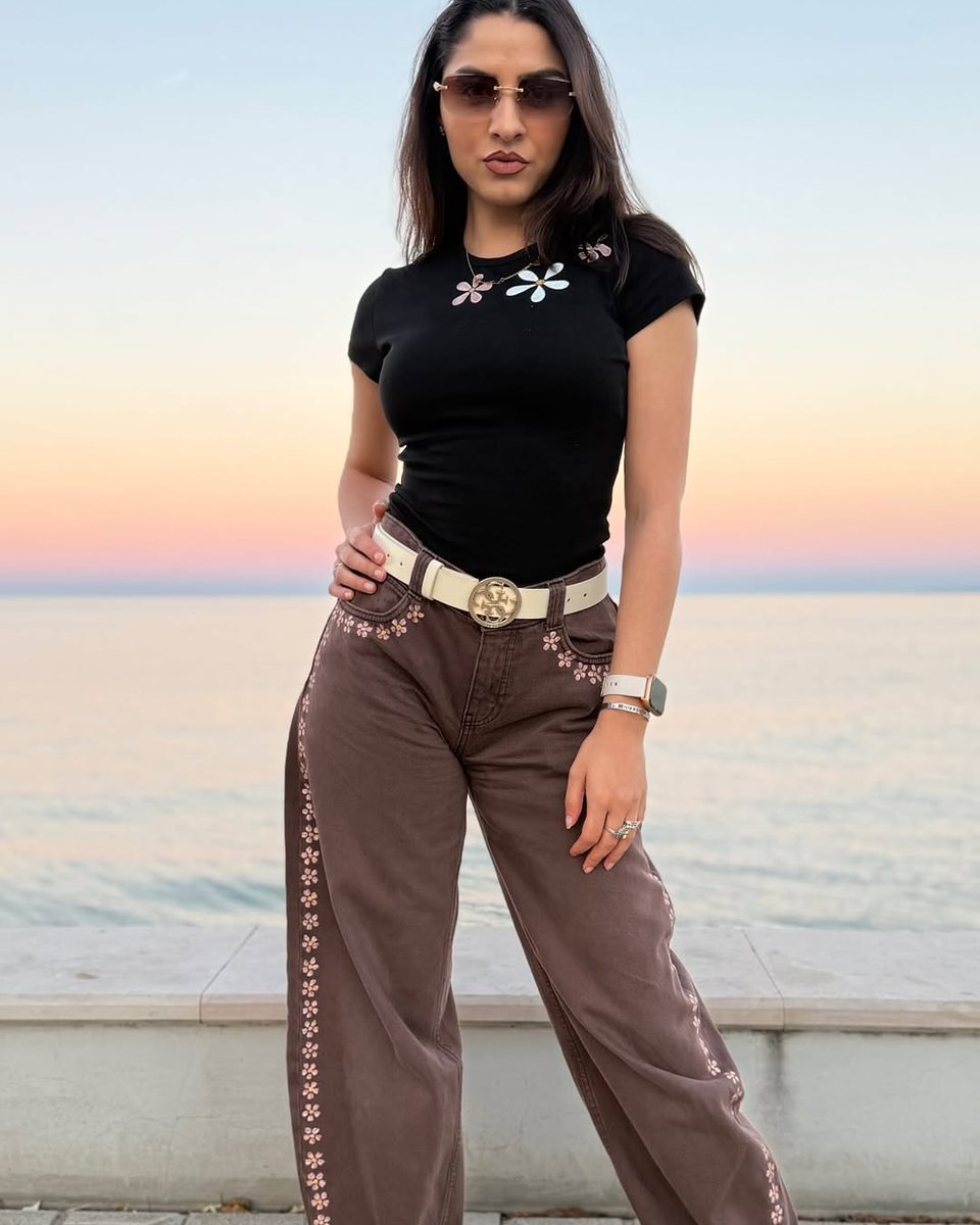 Pantaloni Hazel dipinti a mano con fiori, indossati sul lungomare al tramonto